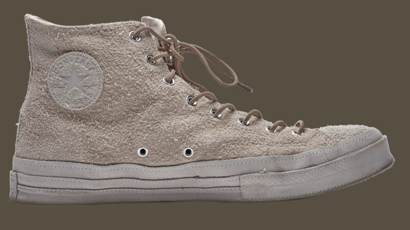 Side profile of a high-top canvas sneaker with lace-up closure and circular ankle patch.