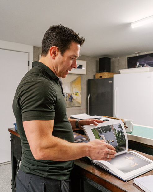 Photographer reviewing printed contact sheets and digital images at a workspace desk.