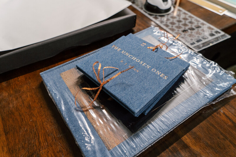 Blue hardcover book with gold lettering on wooden surface next to wrapped materials.