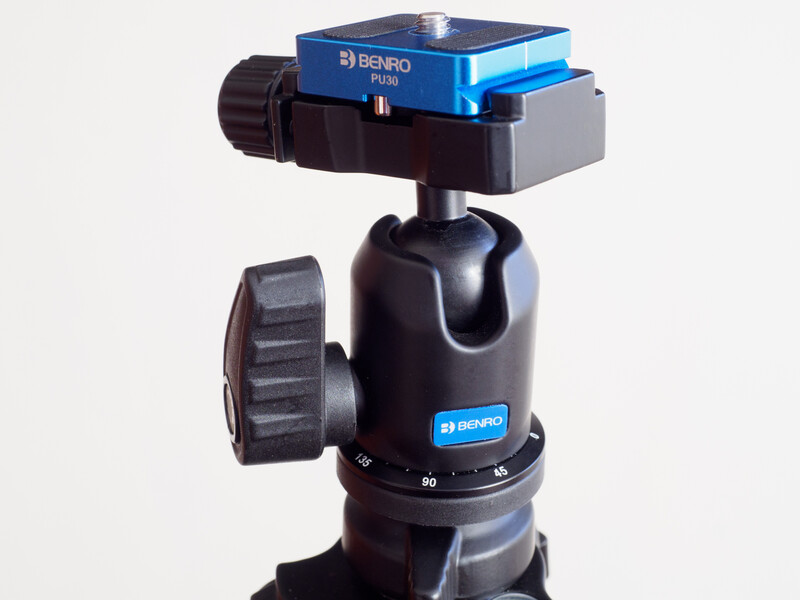 Benro ball head tripod with blue quick-release plate mounted on black stem with friction pan controls.