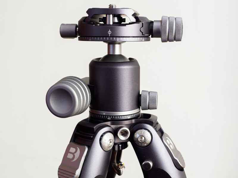 Professional ball head tripod mount with panoramic plate and friction arms on gray background.