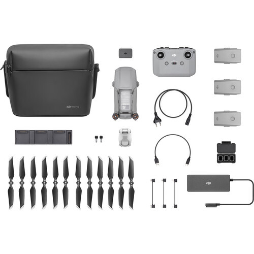 Flat lay of drone equipment including remote controller, batteries, propellers, cables, and carrying case.