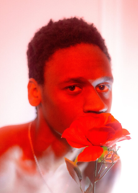 Male subject with red gel lighting overlay holding a translucent geometric crystal form.