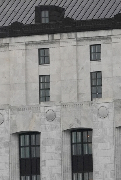 Black and white photograph of a modernist building facade with symmetrical windows and circular details.