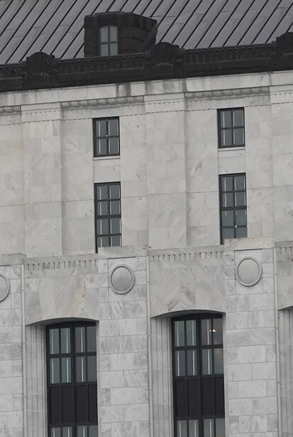 Symmetrical black and white facade of a multi-story institutional building with regularly spaced windows and circular decorative elements.