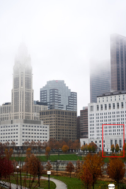 Urban skyline with tall buildings obscured by heavy fog and mist.