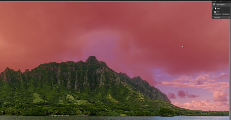 Dramatic tropical mountain ridge with steep green cliffs under a vivid pink and purple sunset sky.