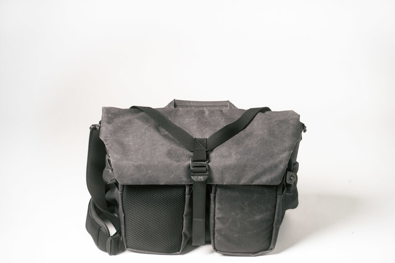 Gray canvas and black nylon camera shoulder bag with multiple compartments and mesh pockets.