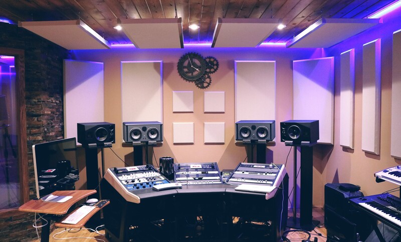 Professional music production studio with mixing console, studio monitors, and acoustic treatment panels.