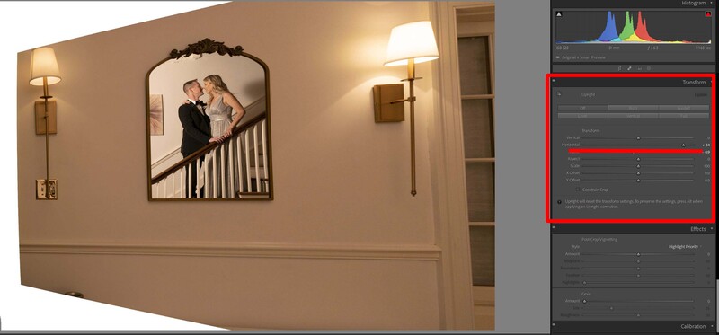 Wedding couple posing on a staircase, photographed in a framed portrait displayed on a beige wall with sconces.