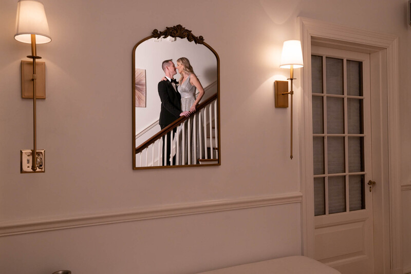 Framed portrait of a couple on a staircase displayed on a bedroom wall.