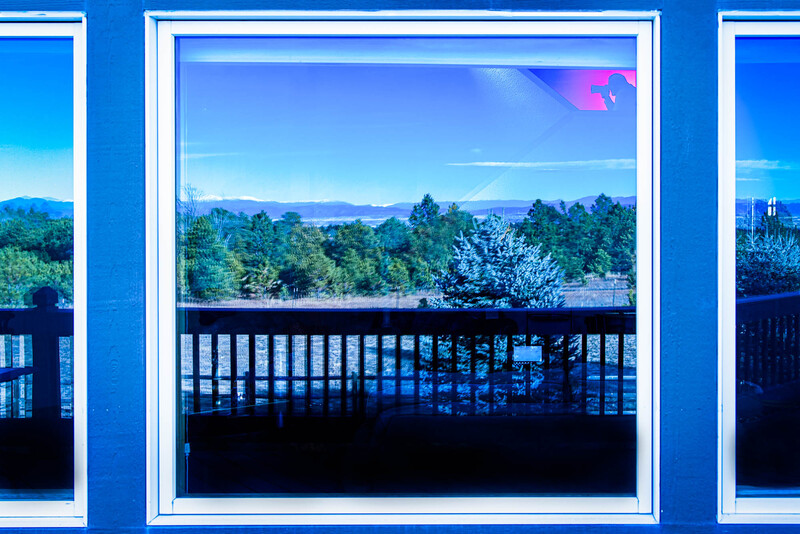 Framed view of forested mountains and valley through a railing, shot in cool blue tones.