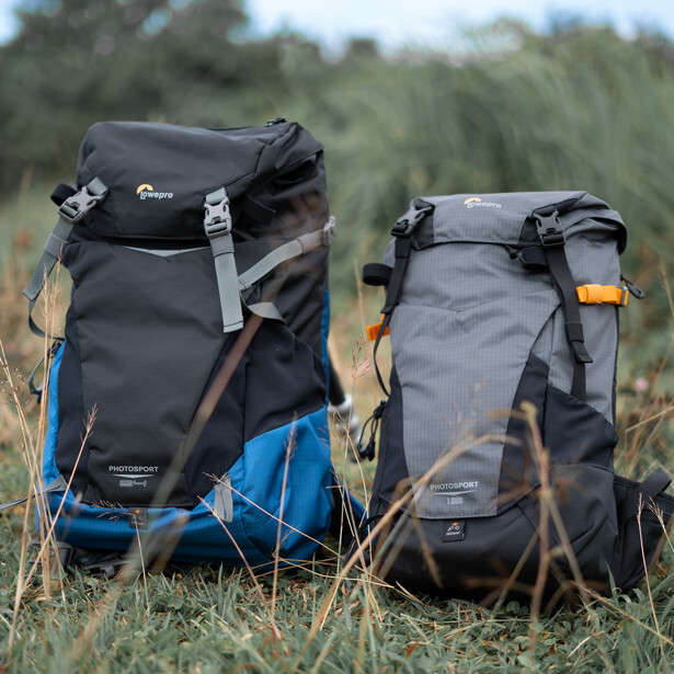 Two hiking backpacks displayed side by side in tall grass outdoors.