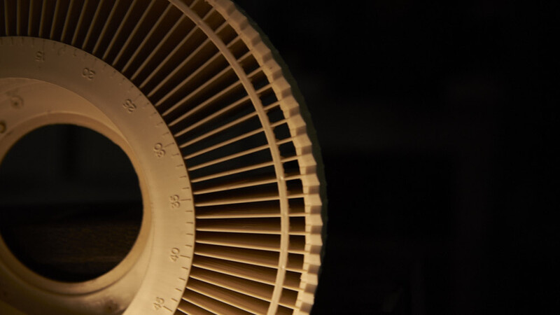 Close-up of an industrial fan motor with radial cooling fins arranged in a circular pattern against a dark background.