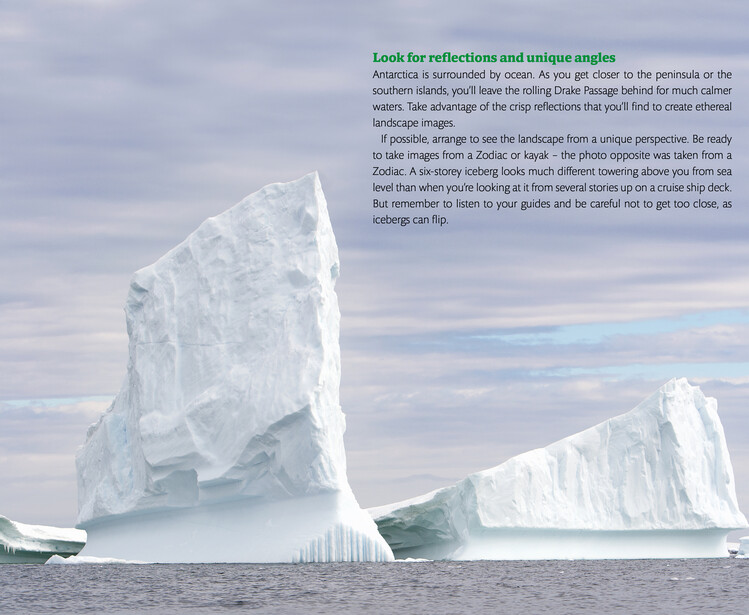 Two large icebergs with bright white faces floating in open water under a cloudy sky.