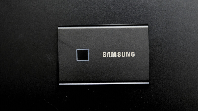 Samsung T7 Shield portable SSD with fingerprint reader against dark background.