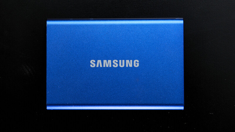 Samsung portable solid-state drive with blue aluminum casing and metallic trim against black background.