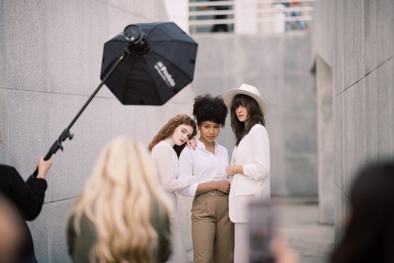 Three women posing together during a studio photoshoot with professional lighting setup.