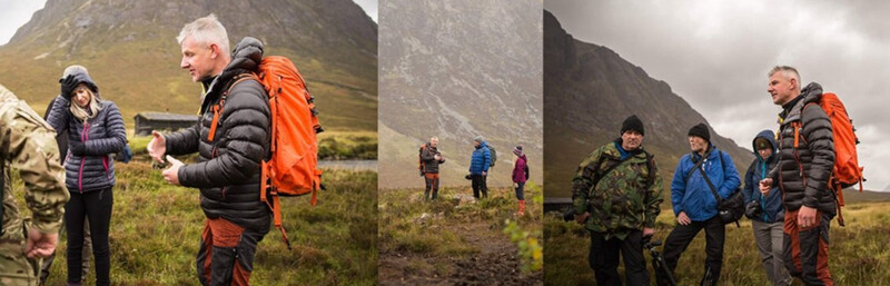 Group of hikers walking across moorland terrain with steep mountain slopes in the background.
