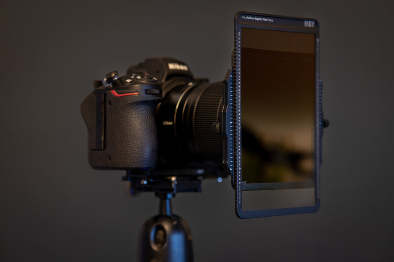 Professional camera mounted on tripod with smartphone display mounted beside it for live view monitoring.