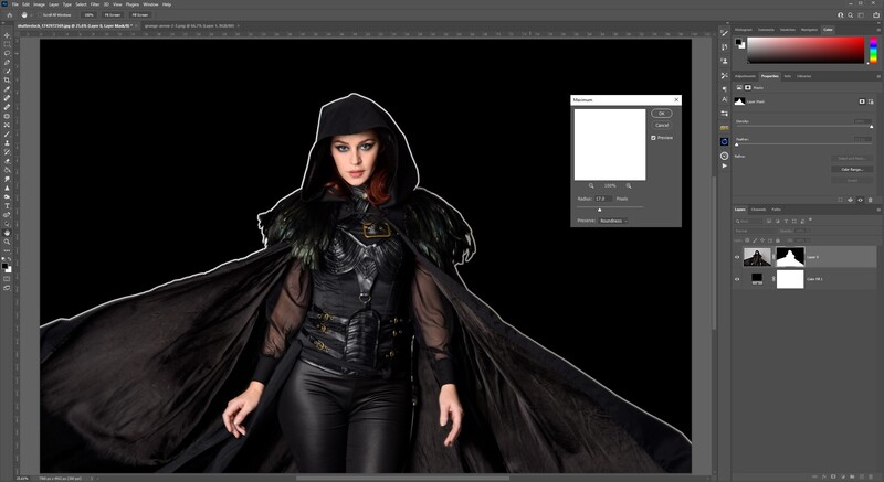 Woman in black gothic outfit with flowing cape against dark background.