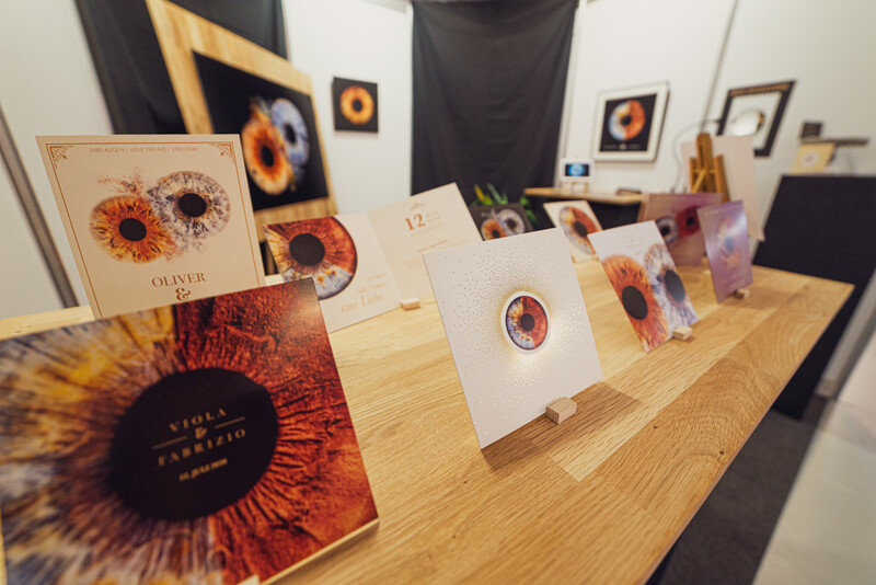Display of printed photographs featuring sunflower close-ups arranged on a wooden table in a gallery setting.