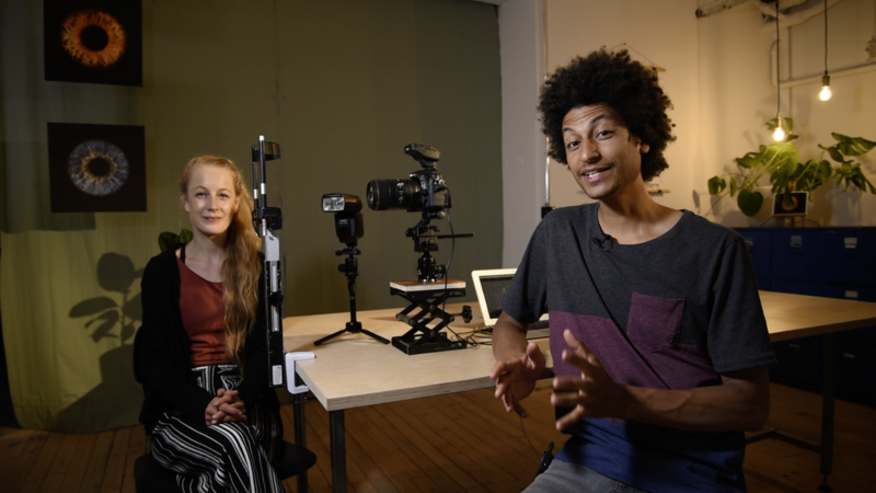 Two people in a video production studio with professional lighting and camera equipment.