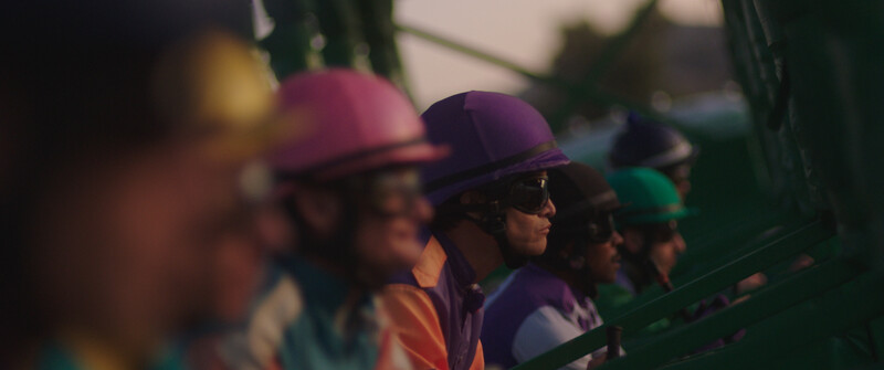 Group of people wearing colorful helmets and sunglasses, shot with shallow depth of field during golden hour.
