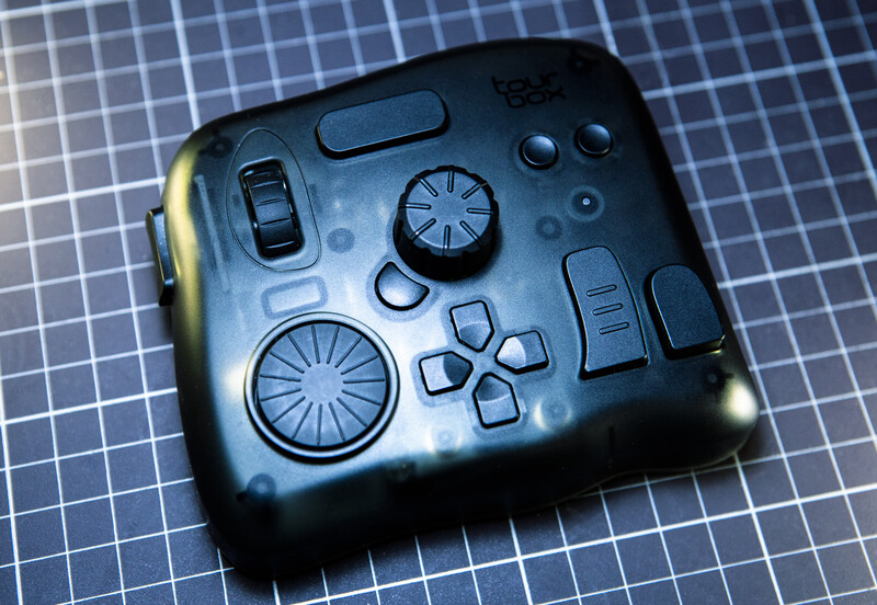 Black game controller with illuminated analog sticks and button layout against blue grid background.