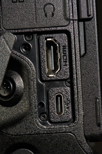 Close-up of camera body controls showing USB and HDMI ports with textured grip surface.