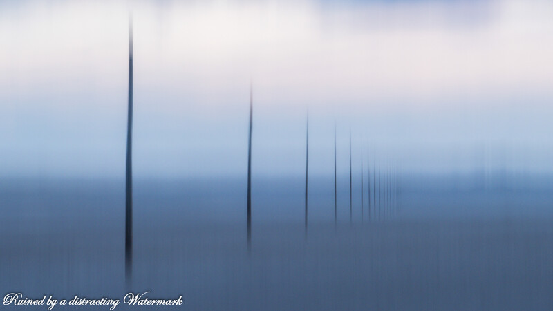 Row of tall spires fading into misty blue atmosphere in minimalist composition.