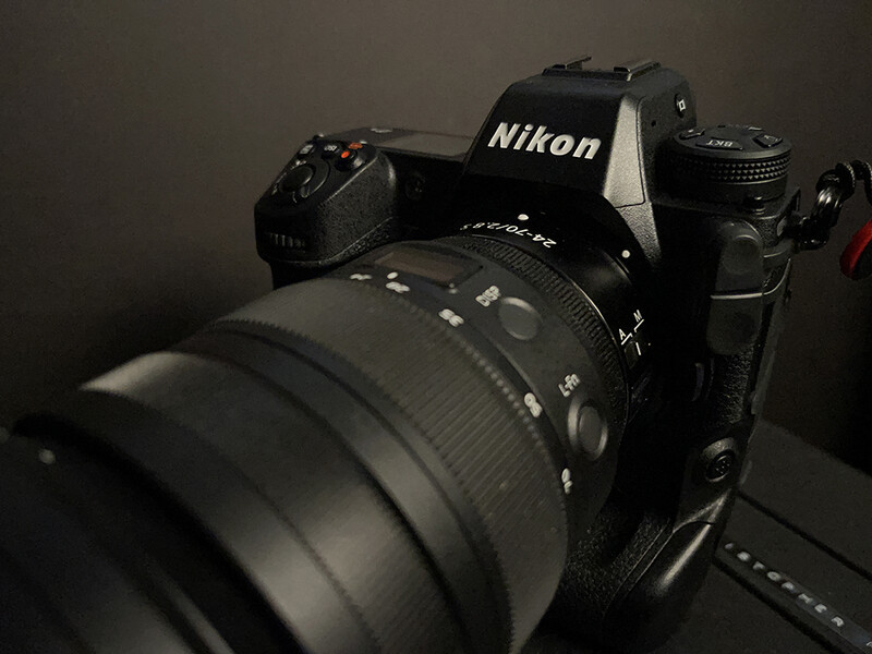 Nikon DSLR camera with attached telephoto lens positioned against dark background.