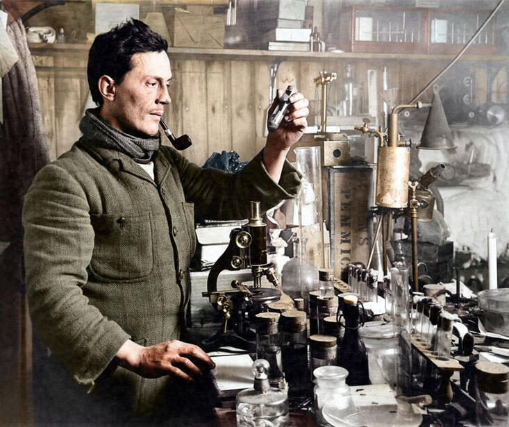 Man in workshop examining mechanical equipment with focused attention amid various tools and machinery.