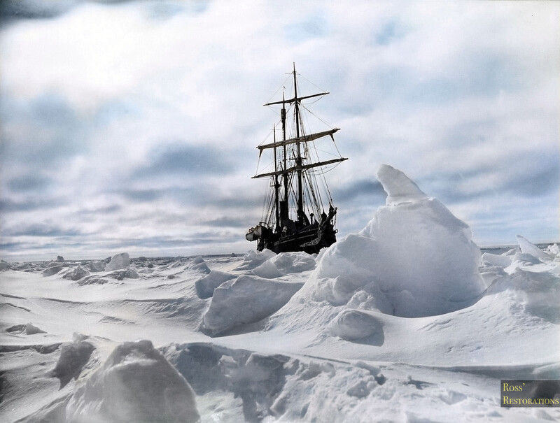 Tall ship with dark sails navigating through massive jagged icebergs in polar waters.