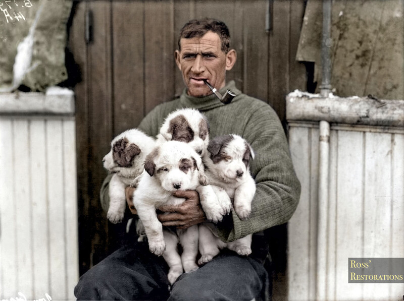 Man holding four white and brown puppies while seated outdoors.