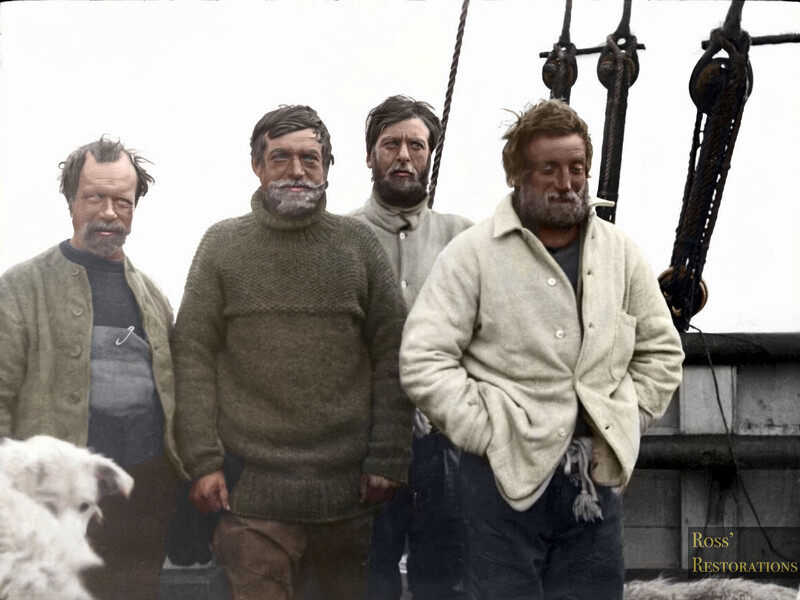 Four men standing together on what appears to be a boat or ship, with rigging and pulleys visible in the background.