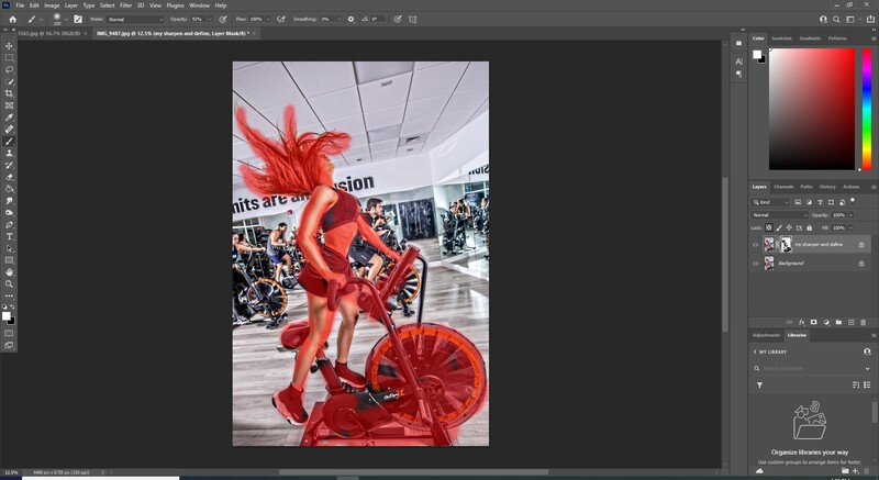 Bright red sculptural figure on a stationary bike in an indoor public space.