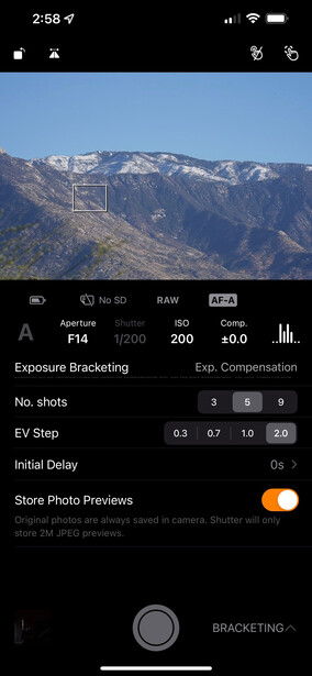 Screenshot of camera app showing mountain landscape with snow peaks and exposure settings displayed.
