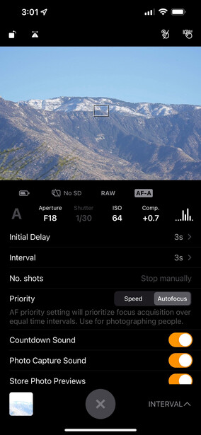 Screenshot of smartphone camera app showing mountain landscape with snow-capped peaks and settings panel visible.