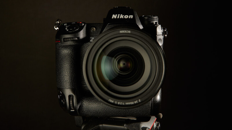Nikon Z series DSLR camera with attached telephoto lens and battery grip, photographed against a dark background.