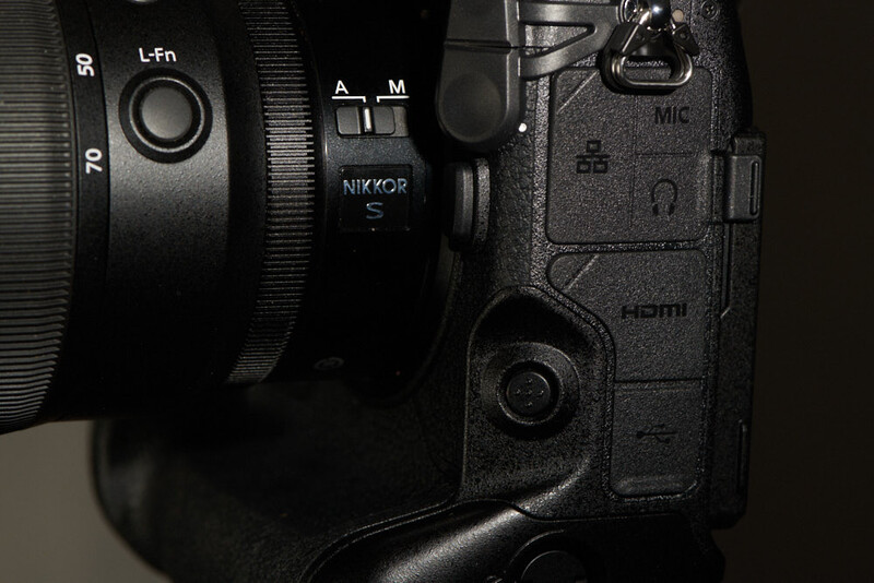 Close-up of a Nikon DSLR camera body showing the grip, control dial, and ports including HDMI and microphone input.