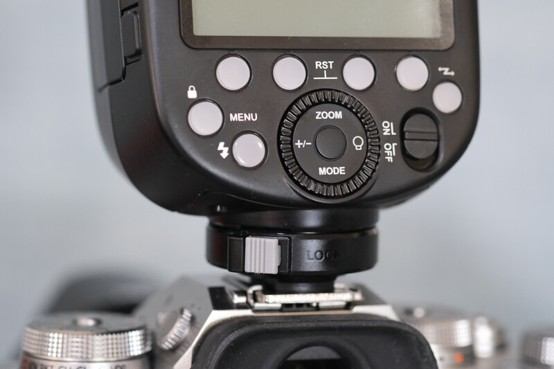 Flash unit mounted on camera body, showing control dial, buttons, and LCD screen.