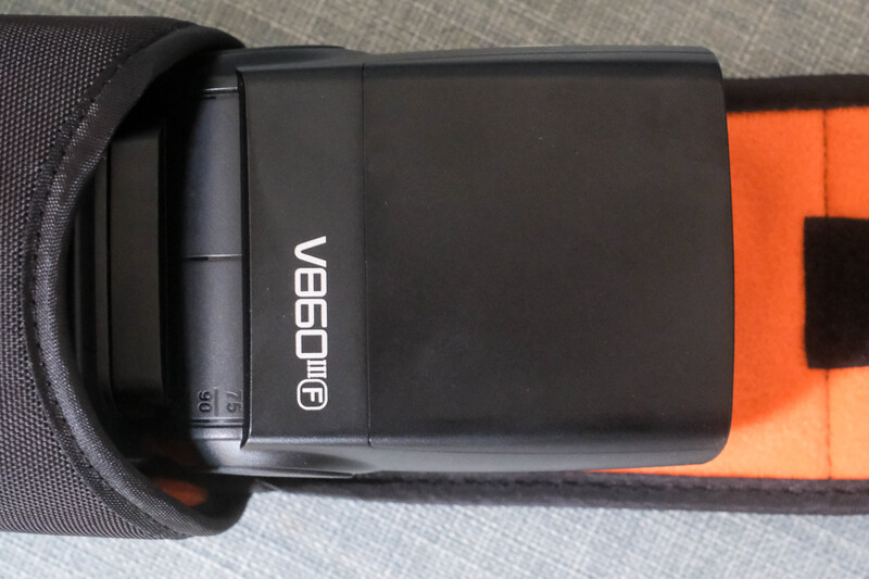 Verifocal VR headset viewer with black housing and orange accent strap against fabric background.