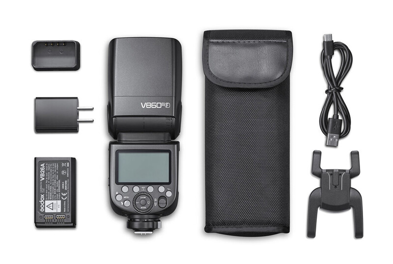 Godox camera flash with battery, charger, USB cable, carrying case, and accessories laid out flat.