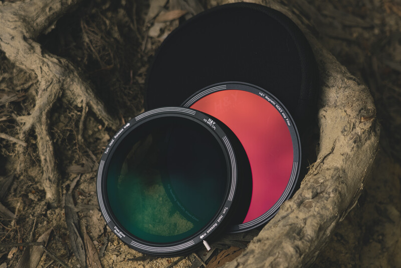 Two round camera filters with green and red tints lying in a textured stone surface.