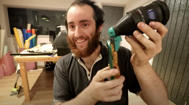 Photographer holding a telephoto lens and thermal imaging camera in an indoor studio setting.
