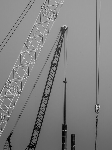 Industrial crane and lattice tower structures shot from below in black and white.