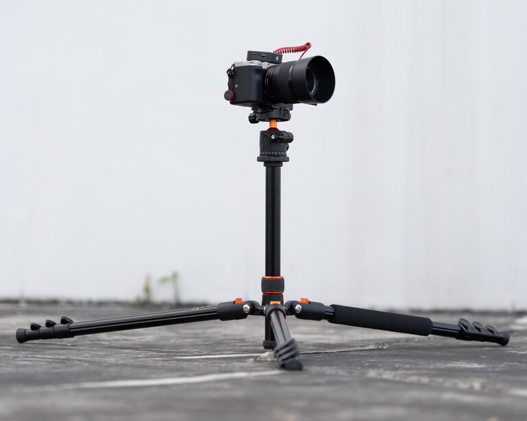 Professional camera rig mounted on tripod with stabilizing arms extended on concrete surface.