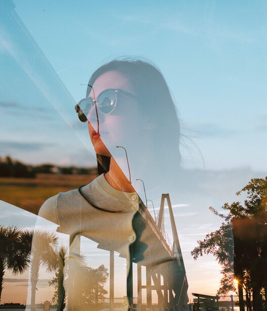 Double exposure portrait blending a person's profile with a rural landscape at golden hour.