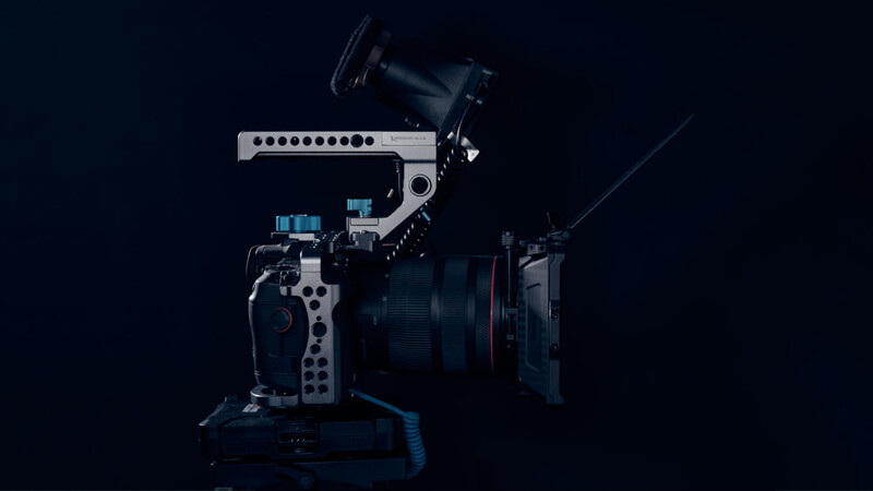 Professional cinema camera rig with white support arm, external monitor, and wireless microphone mounted on dark background.